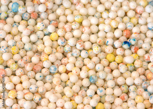 Close up view of many hard round small gum ball type candy. Speckled with color.