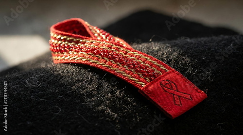 Embroidered red ribbon on dark textured fabric surface.