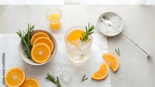 Overhead View of Gin and Tonic Preparation with Fresh Orange Slices Rosemary Sprigs and Ice