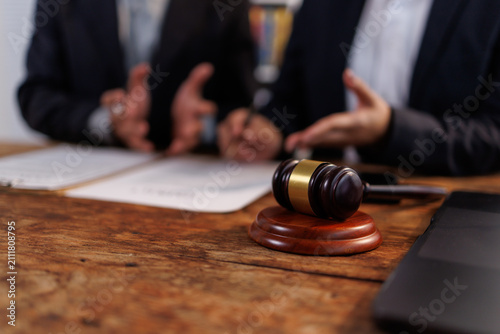 Obraz na plátně Gavel on a rustic wooden desk, two business professionals discussing legal docum