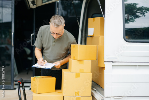 Professional courier holding parcel beside delivery van. Logistics, shipping, ecommerce, warehouse, last mile delivery, express service and reliable package transportation.