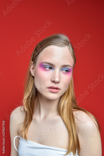 Canvastavla A woman with bright, expressive eye makeup on a red background