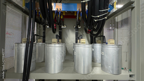 Foto Industrial power factor capacitor bank inside electrical control cabinet with copper busbars, heavy wiring, and cable connections
