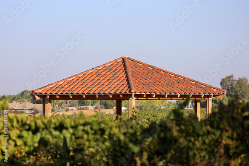 View of a wooden gazebo with two tone classic terracotta Spanish clay tile roof.