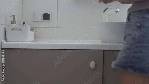 Woman cleaning the bathroom vanity and wiping the countertop with a cloth during a household cleaning routine
