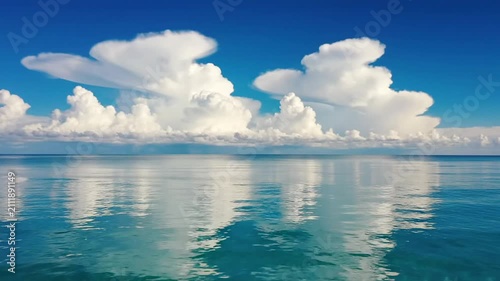 Tranquil turquoise ocean water under scenic white clouds.