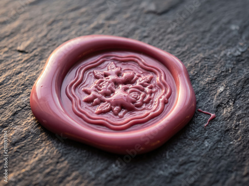 Pink wax seal with floral design on a dark wooden table background