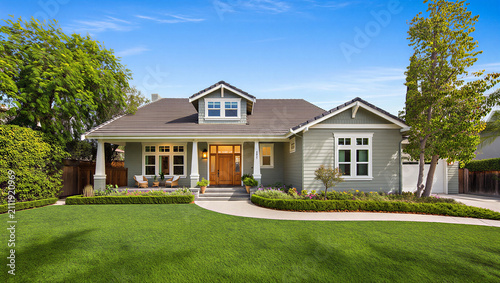 Fotografie Single story suburban ranch home with green siding and manicured lawn real estat