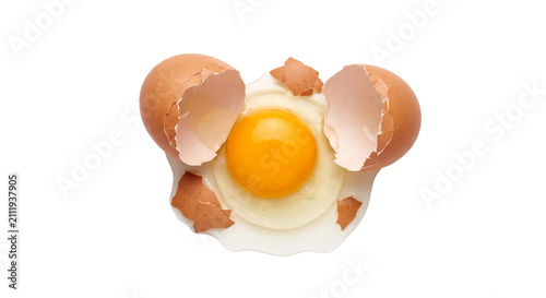 Fotografía Broken brown egg with bright yellow yolk and scattered shell fragments