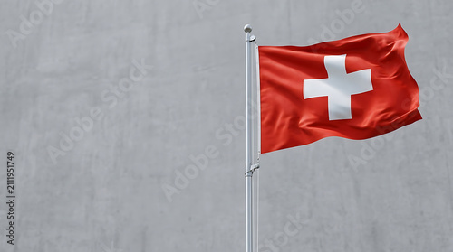 Switzerland flag and Swiss flag as a national symbol on a flagpole waving flag for independence day celebrations against a gray wall background