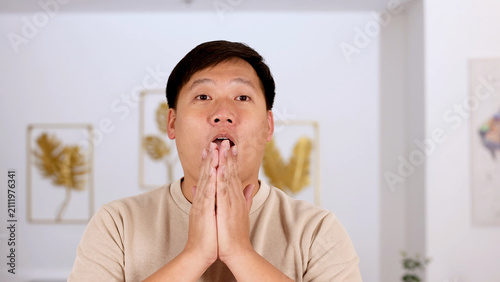Konstfotografi Surprised Asian Man Covering Mouth with Hands in Modern Living Room
