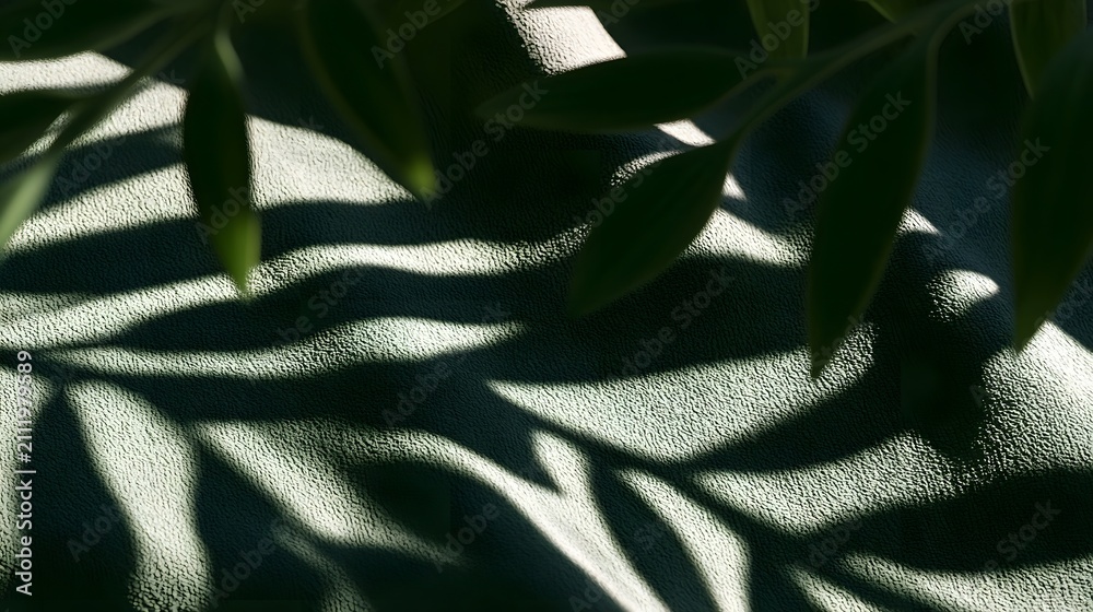 Fototapeta premium Leafy branches cast intricate shadows on a textured green fabric surface under soft natural lighting