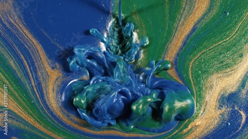 Blue, green and gold acrylic paints swirl and mix together
