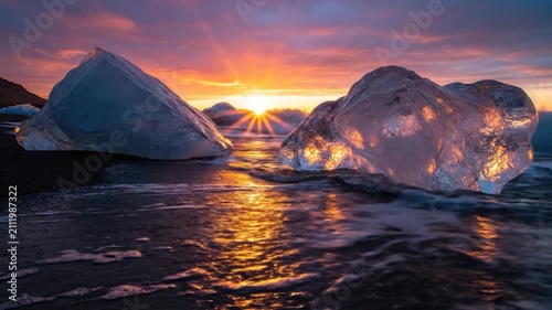 Glacial ice blocks glow on a black sand beach at sunset