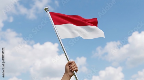 Low angle view of hand holding Indonesian flag waving against sunny blue sky background