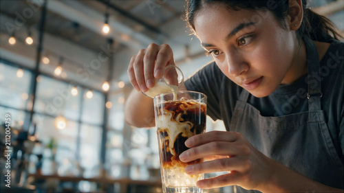 close-up of a Latin American barista pouring cream into a cold espresso with ice and syrup, a poster about cold brew coffee for Generation Z, copy space for text for National Coffee Day