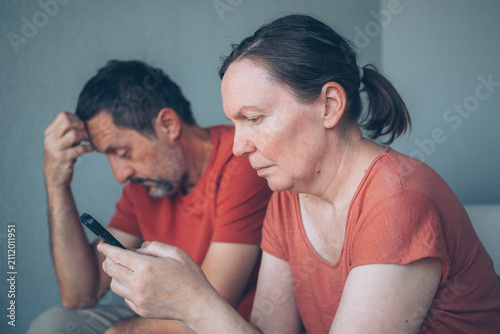 Obraz na plátně A middle-aged couple sit side by side, woman absorbed in her smartphones, illust