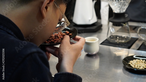 Schilderij op canvas Close-up of a coffee professional inspecting and smelling roasted coffee beans during a quality evaluation process in a specialty coffee shop