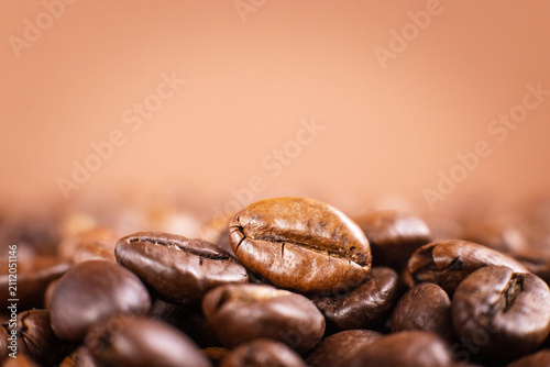 Close-up of roasted coffee beans and a coffee pod on a brown background