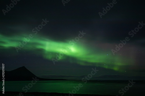 Fotografie Green Northern lights Aurora Borealis exploding in the night sky in Iceland