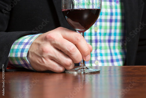 Caucasian man is enjoying a glass of red wine. Business outfit.