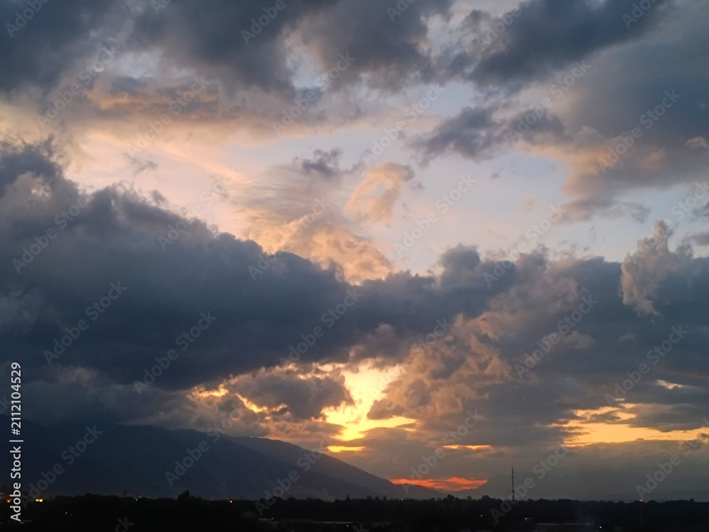 Fototapeta premium Dramatic sunset sky with golden clouds over mountain silhouette, Yunnan twilight landscape