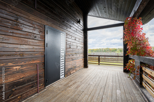 Canvastavla rustic wooden porch features dark-stained plank walls, a modern black metal door