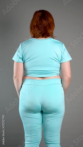 Unrecognizable curvy woman performs exercises for muscles of upper back and shoulder joint, posture correction and physical therapy concept on gray background