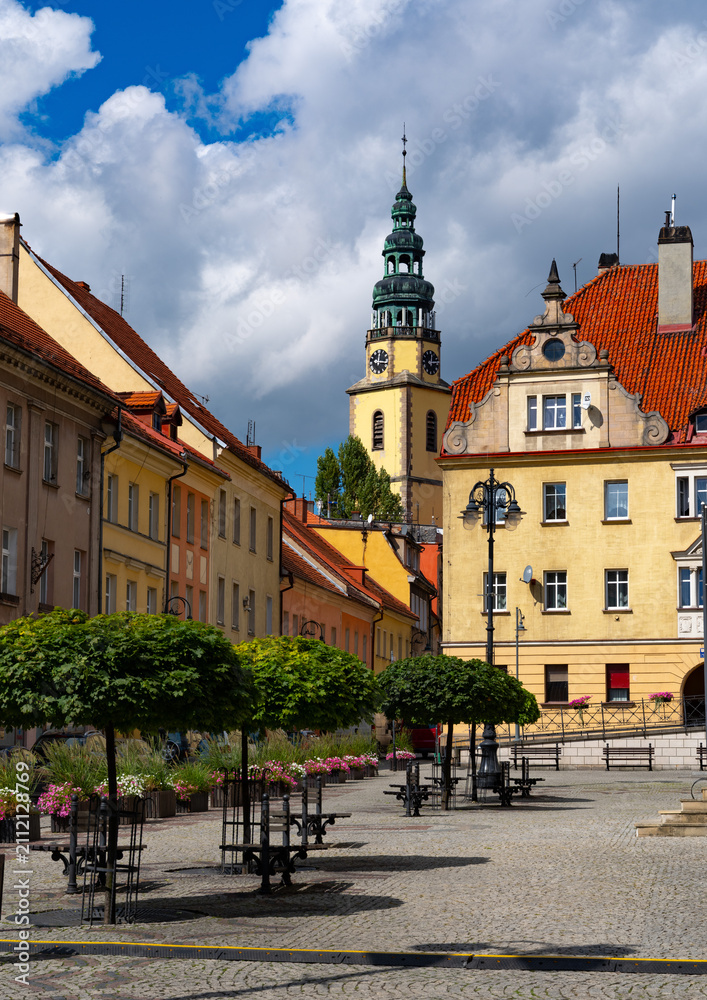 Obraz premium 2025-09-03; Charming old town square with cobblestones, benches and a high spire. Bystrzyca Klodzka. Poland.
