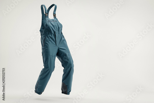 Teal work overalls hanging on white wall, durable canvas bib pants with pockets and straps, minimal studio apparel photo for retail catalog