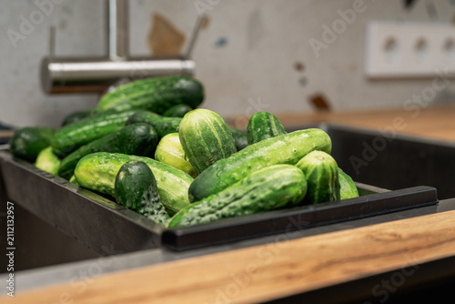Картината върху платно Fresh homegrown cucumbers in a kitchen sink on a modern kitchen after harvest