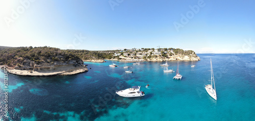 фотографія Landscape of a bay on the island of Mallorca with several boats and Catamaran anchored on the water of a beach with crystal-clear turquoise water