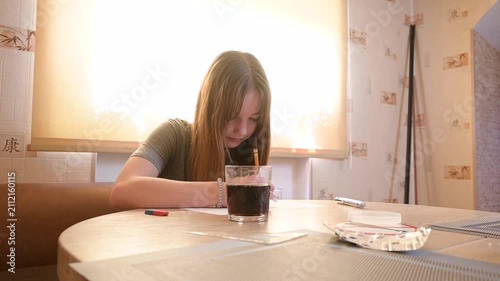Smiling Young Woman Drawing on Paper with Pencil at Kitchen Table with Soda