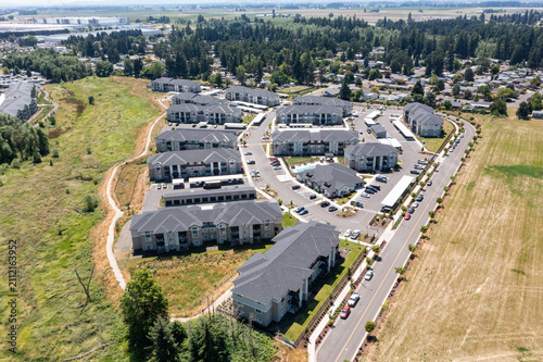 Aerial drone photo of residential neighborhoods and modern apartment communities in Woodburn, Oregon, USA surrounded by farmland and suburban development near Interstate 5