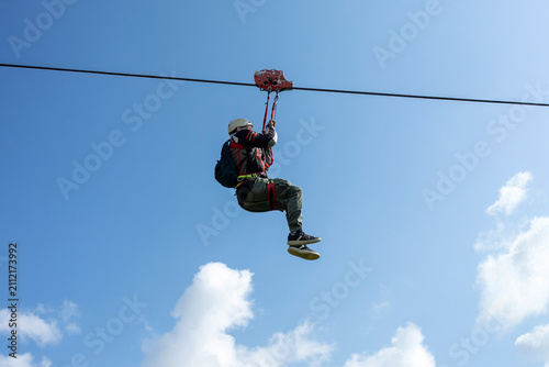 Person on zipline with wide blue sky in background adventure activity in mountain