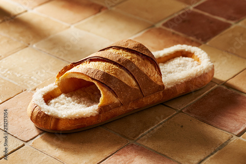 Playful shoe concept of a cozy home slipper designed to look exactly like a crusty baguette bread loaf