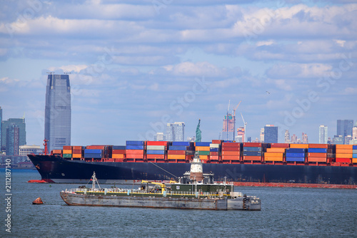 Container ship sails past the Statue of Liberty in New York Harbor, USA.