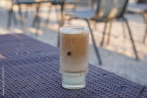 Bild auf Leinwand Creamy iced pistachio latte in a tall ribbed glass served on an outdoor café table with soft natural light and blurred background