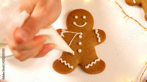 Gingerbread man cookie decorated with white icing on a white surface next to a glass of milk