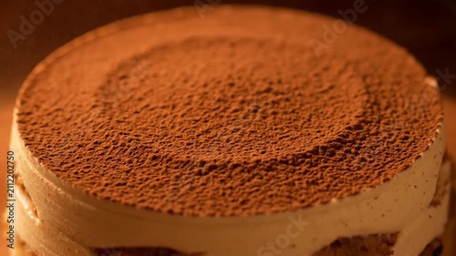 Cocoa powder being sprinkled onto a cream cake