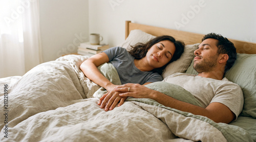 Pareja relajada en la cama con los dedos entrelazados, transmitiendo serenidad, sexualidad consciente y profunda conexión sensorial.