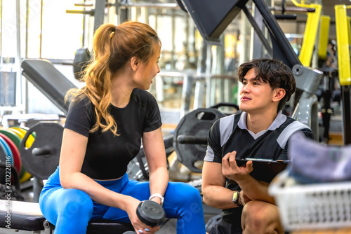 Canvas Print Handsome Asian male personal trainer helping and instructing a fit sportswoman d