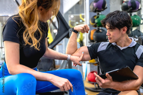 Принти на полотні Excited female client touching and pointing to fitness instructor muscular arm,
