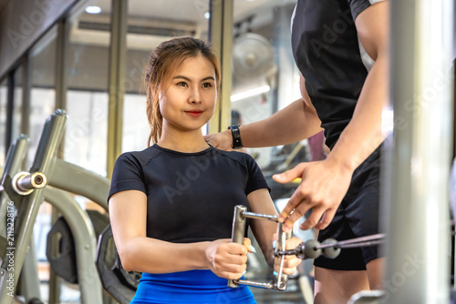 Foto Handsome Asian male personal trainer helping and instructing a fit sportswoman d