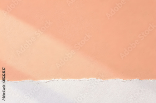 Abstract minimalist paper background with a torn peach colored paper overlapping a plain white surface
