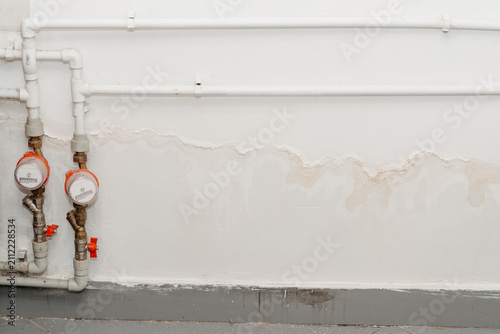 streaks of water on white wall and two water meters, consequences of flooding, water supply accident, sewer breakout, need for repairs