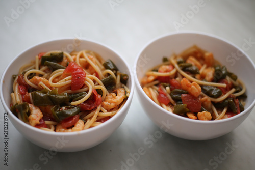 Bowl with spaghetti, shrimps, tomatoes and herbs