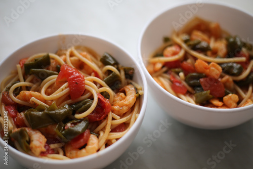 Bowl with spaghetti, shrimps, tomatoes and herbs