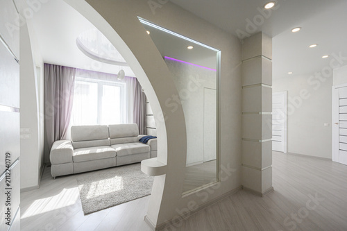 Bild auf Leinwand bright modern entryway features a curved gypsum‑board partition, a large mirror