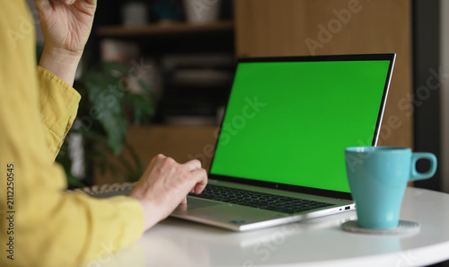 Laptop with green screen chroma key mockup for content replacement.